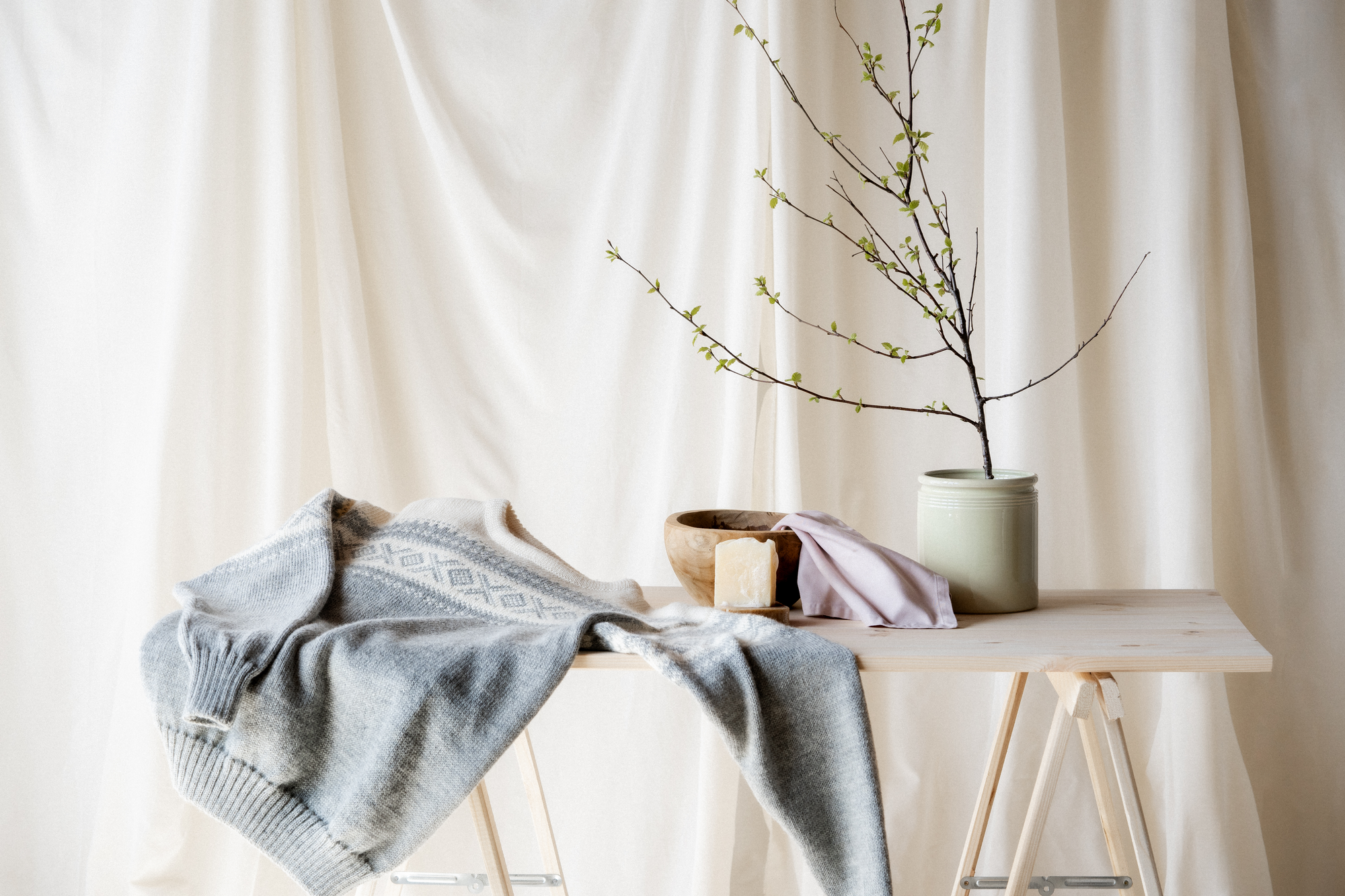 Gr&aring; Cortina genser liggende p&aring; et bord klar til h&aring;ndvask