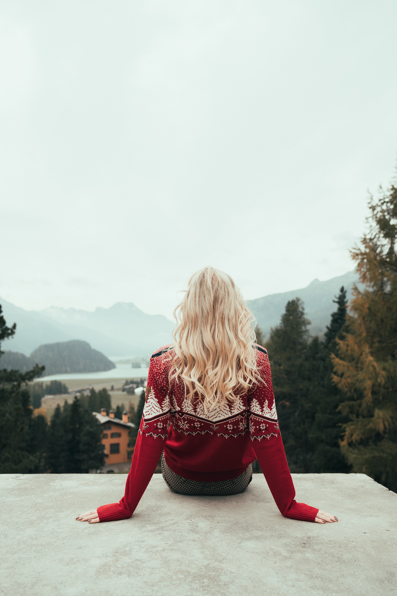 Dale julegenser ute i norsk natur. Kvinnelig blond modell med ryggen til kamera sittende i en trapp