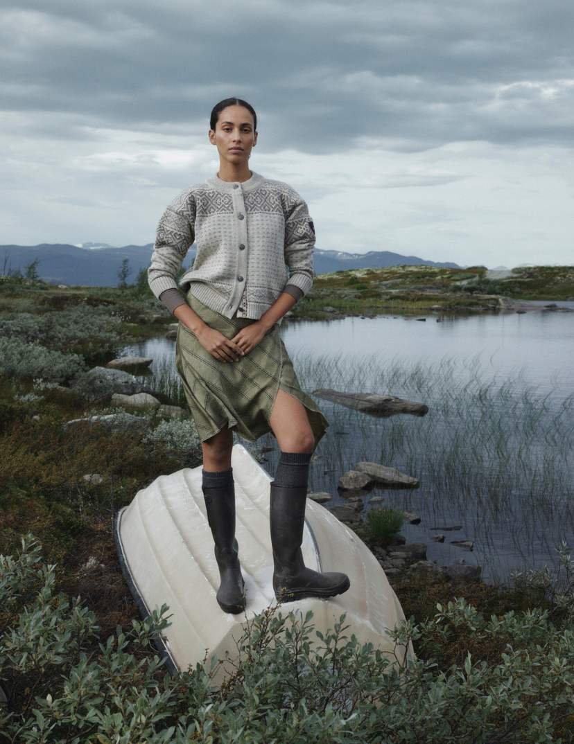 Hannah genser i Nature undyed ullkvalitet. Kvinnelig modell i norsk natur med m&oslash;rke skyer i bakgrunn