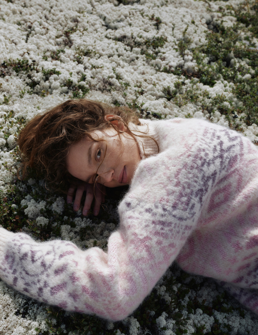 Highland genser i Garzato ullkvalitet. Kvinnelig modell ligger &aring; en stein i norsk natur. Hilsen Dale of Norway